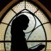 Silhouette of a woman reading in front of Islamic-patterned window. Peaceful and cultural ambiance.
