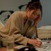 Woman sitting at a table searching job listings, focused and determined.