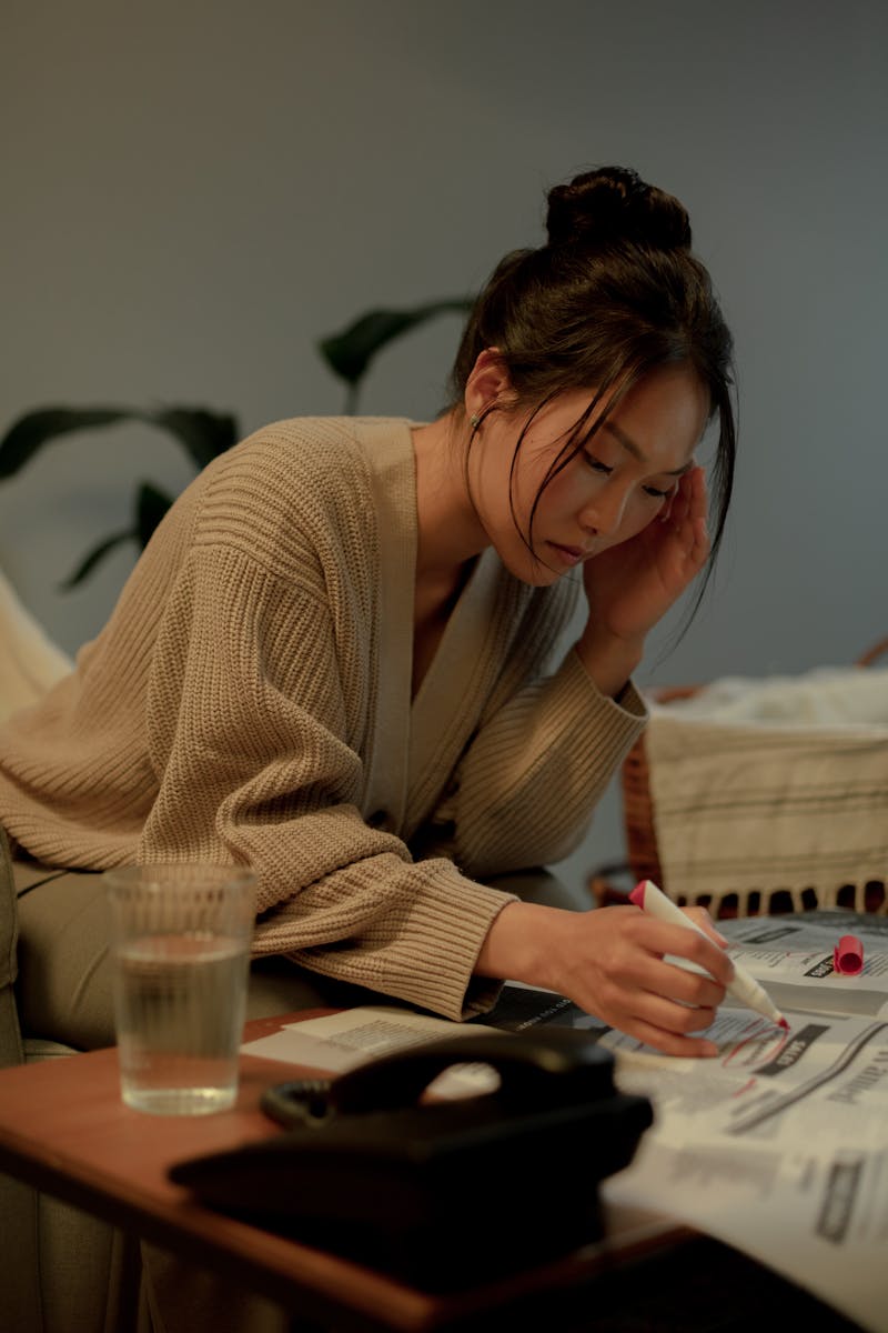 Woman sitting at a table searching job listings, focused and determined.